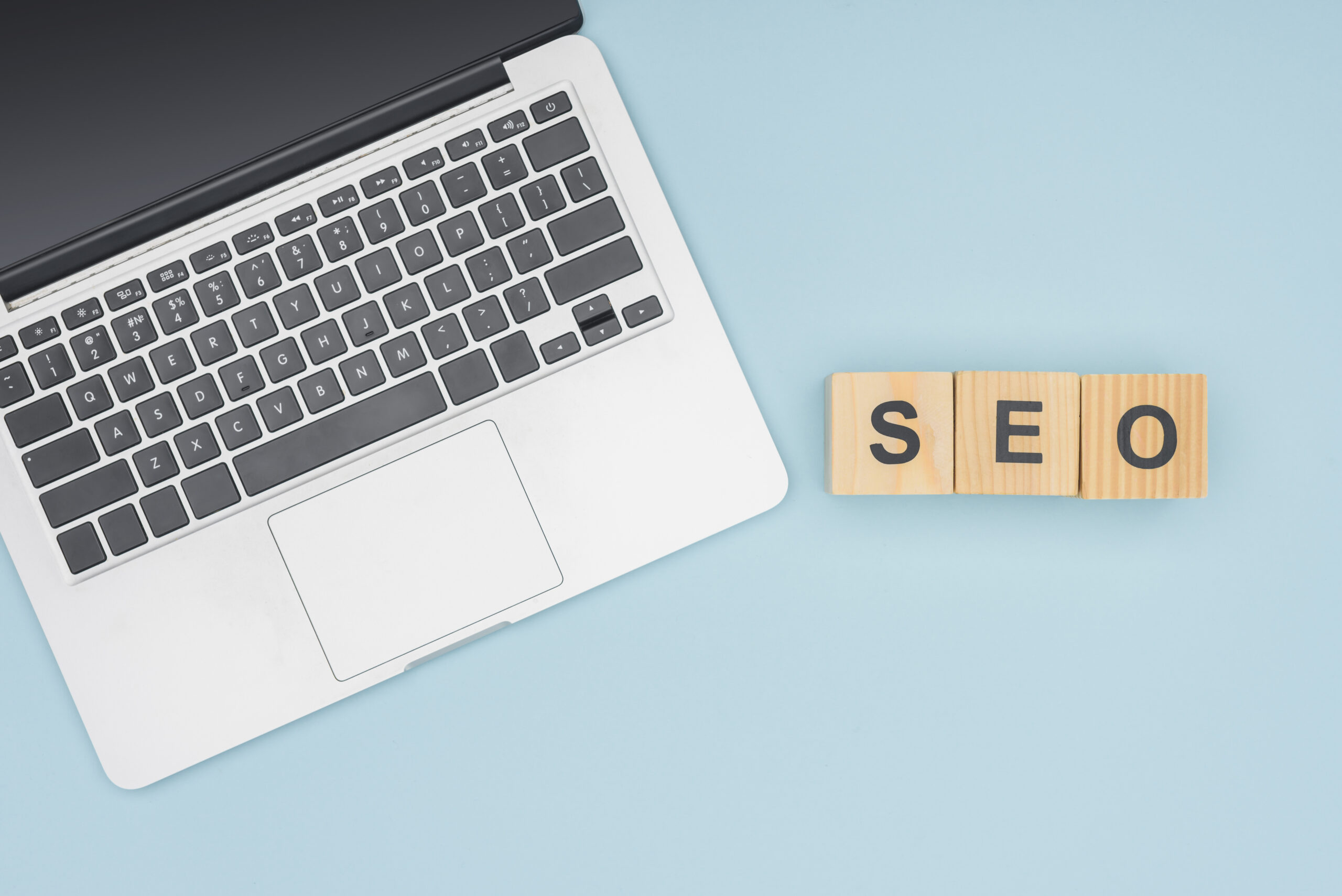 Top view of laptop near cubes with letters on light blue background